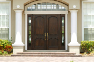 Beautiful mahogany double doors with sidelights at stately entrance of a home with ornate white columns on either side