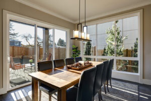 Luxury dining area that looks out through large sliding glass patio doors on outdoor patio with table and chairs that's surrounded with wood privacy fencing