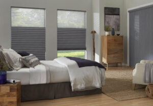 Luxury bedroom with slate-gray horizontal tandem honeycomb shades on two windows and matching vertical shades on a patio door